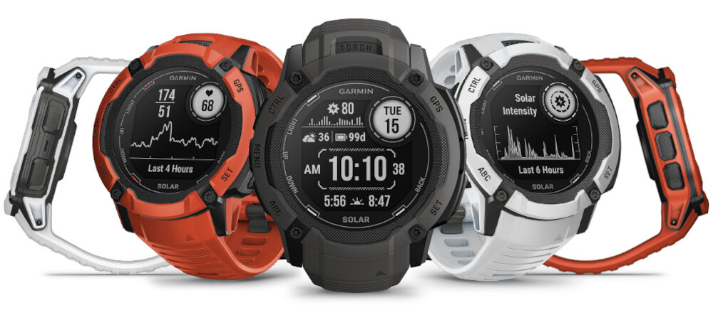 Trzy smartwatche z okrągłymi tarczami, wyświetlające różne dane, takie jak czas, datę i wykresy. Na tarczach widoczne są napisy: \'GARMIN\', \'SOLAR\', \'Last 4 Hours\', \'Solar Intensity\', \'Tue 15\', \'10:10:38\'.