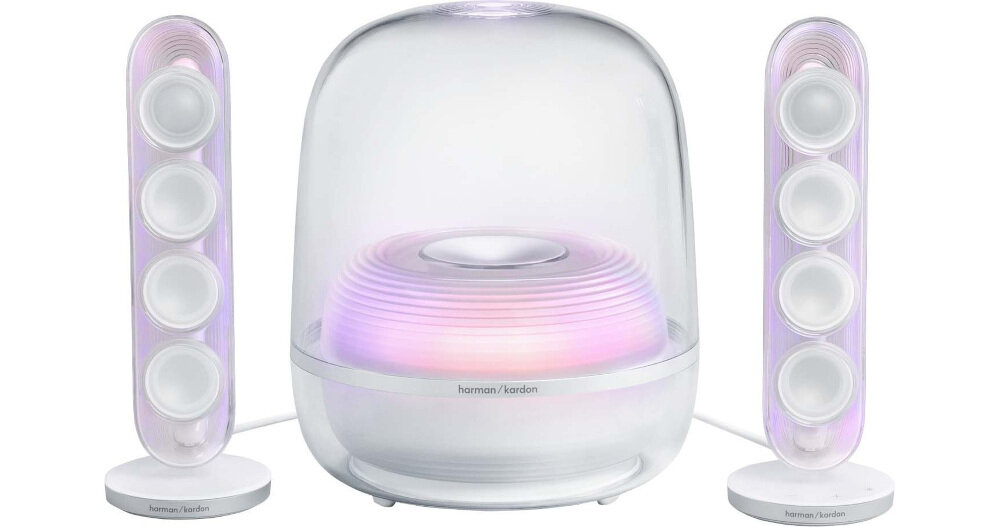 Na obrazie widoczny jest zestaw głośników z przezroczystymi obudowami, w tym centralny subwoofer i dwa pionowe głośniki satelitarne. Na subwooferze znajduje się logo \'harman/kardon\'.