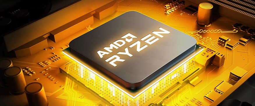 Obraz przedstawia procesor z napisem \'AMD RYZEN\' umieszczony na złotej płycie głównej. Procesor jest podświetlony, co podkreśla jego centralne położenie.