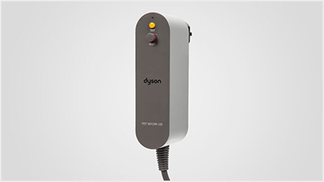 Urządzenie z logo \'dyson\' na szarej powierzchni, z przyciskiem i napisem \'TEST BEFORE USE\'.
