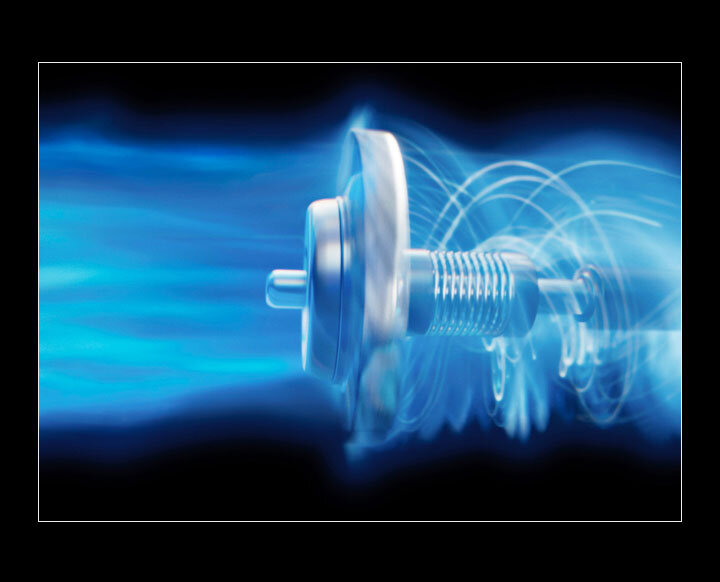 Obraz przedstawia wirujący element mechaniczny z efektem niebieskiego rozmycia, sugerującym ruch powietrza. Element ma metaliczny wygląd z widocznymi spiralnymi detalami.