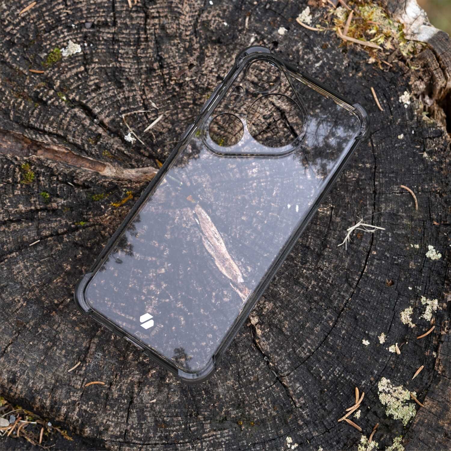 Przezroczyste silikonowe etui na telefon z widocznymi otworami na aparat, leży na pniu drzewa. Na etui znajduje się małe logo w kształcie białego symbolu.