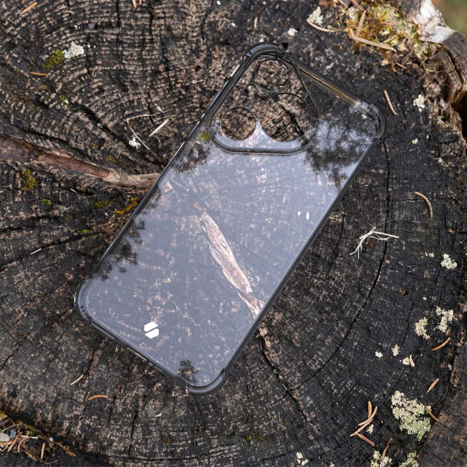 Przezroczyste silikonowe etui na telefon leży na pniu drzewa. W tle widoczne są słoje drewna i drobne fragmenty mchu.