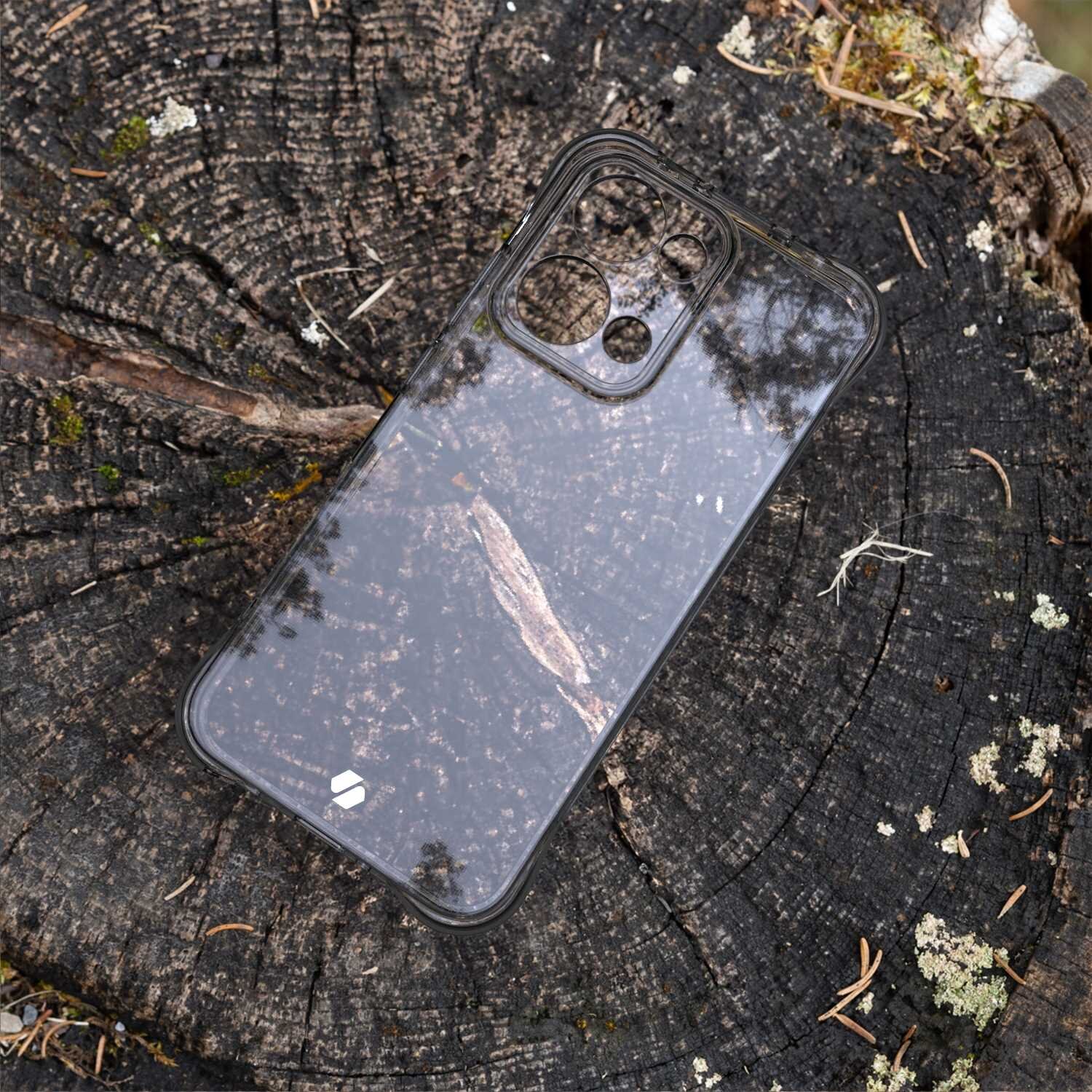 Przezroczyste silikonowe etui na telefon leży na pniu drzewa. Widać wycięcia na aparat i logo producenta w dolnym rogu.