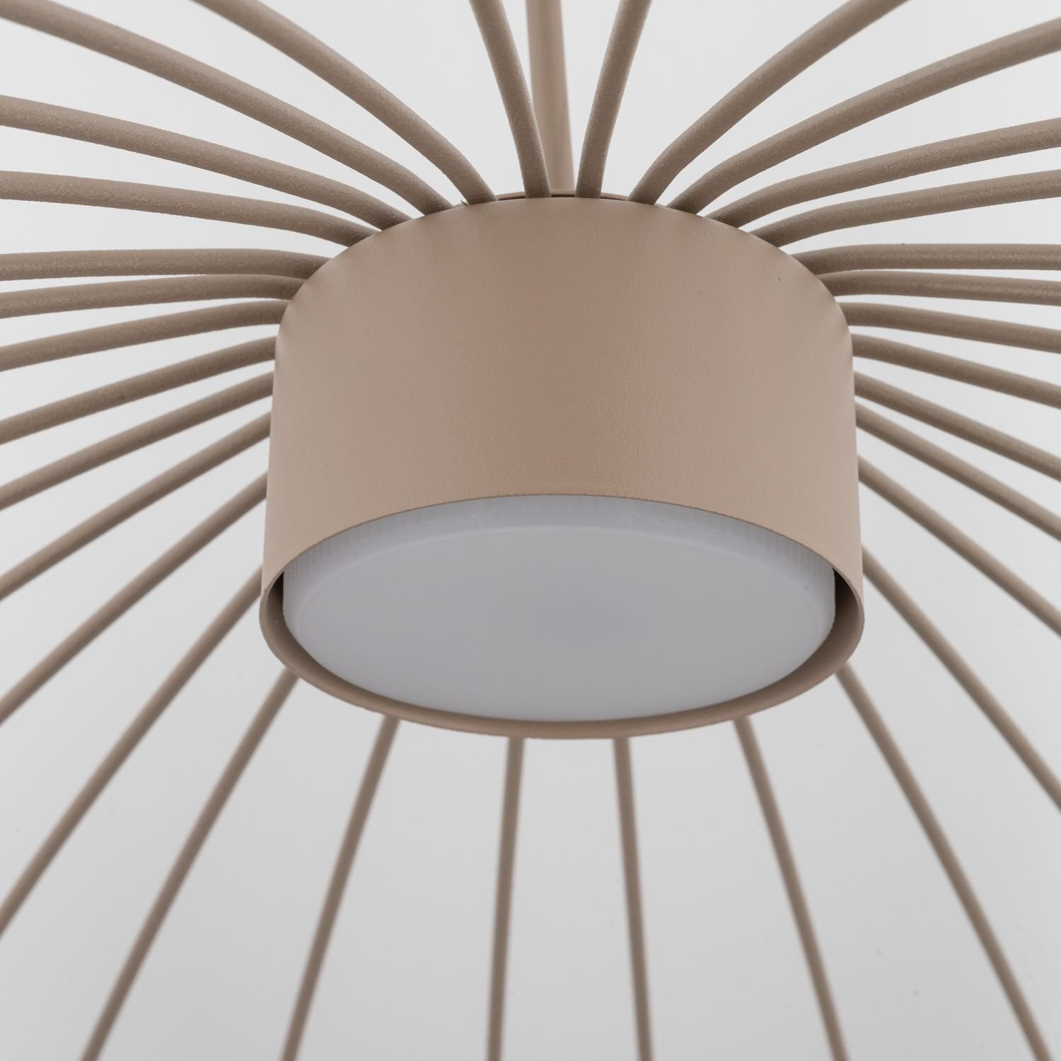 Lampa wisząca z beżowym cylindrycznym elementem centralnym i promieniście rozchodzącymi się prętami. Dolna część lampy jest biała i płaska.