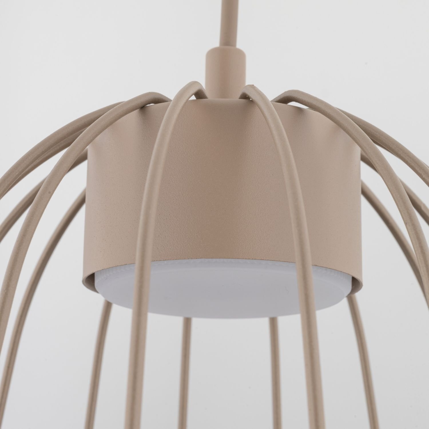 Beżowa lampa wisząca z metalowymi prętami rozchodzącymi się od centralnego punktu. Dolna część lampy jest biała i okrągła.