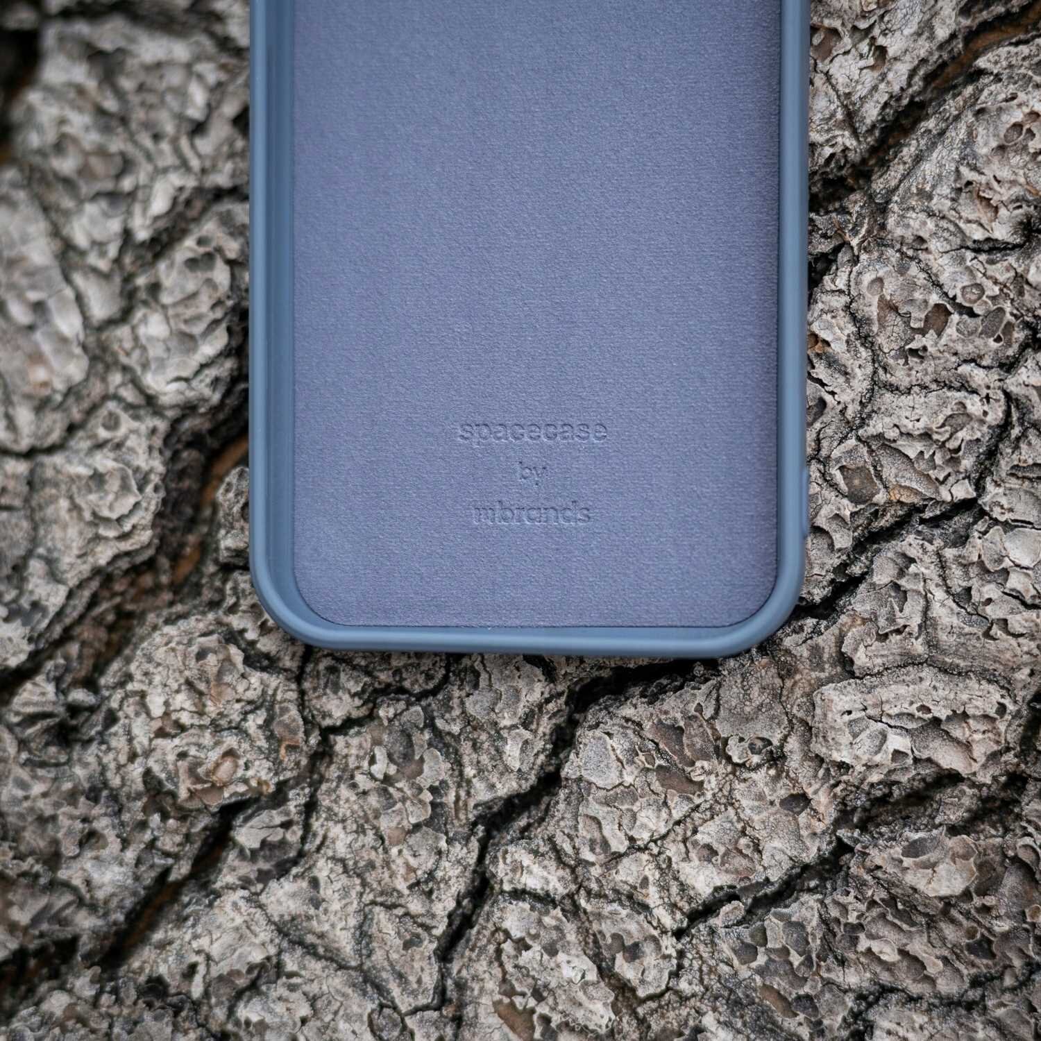 Niebieskie silikonowe etui leży na tle kory drzewa. Na etui widoczny jest tekst: \'spacecase by ribcases\'.