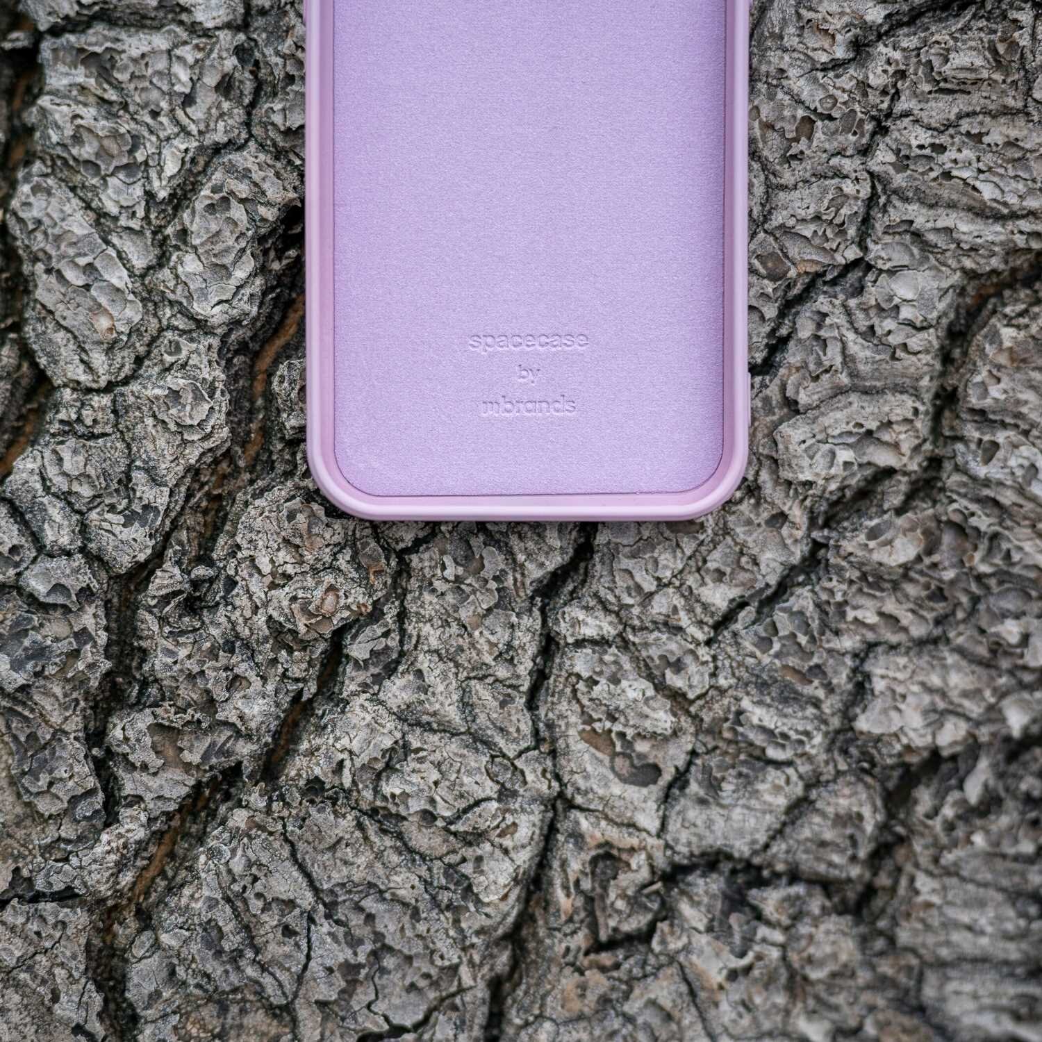 Różowe silikonowe etui leży na tle kory drzewa. Na etui widoczny jest tekst: \'spacecase by mbrands\'.
