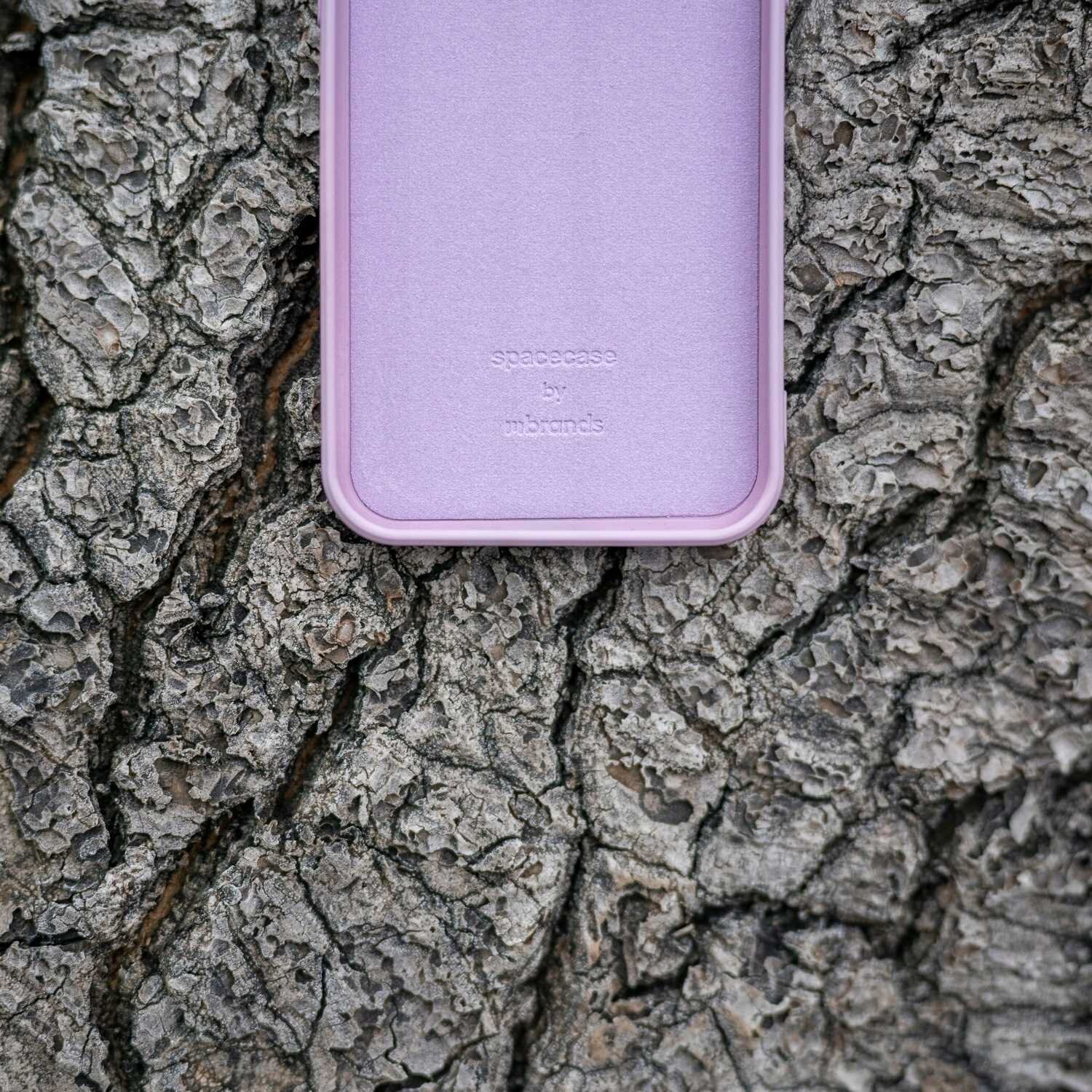 Różowe silikonowe etui leży na tle kory drzewa. Na etui widoczny jest napis: \'spacecase by mbands\'.