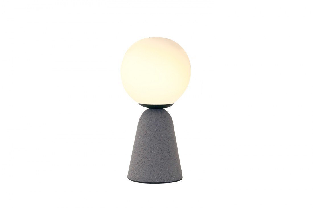 Na obrazie widoczna jest lampa stołowa o nowoczesnym designie, składająca się z kulistego klosza emitującego ciepłe światło, umieszczonego na stożkowej podstawie w szarym kolorze.