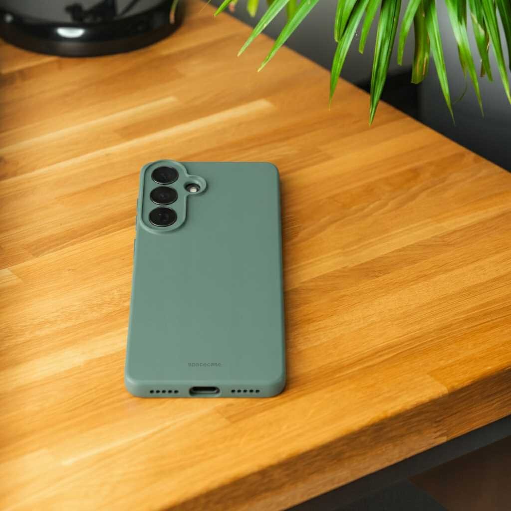Zielone silikonowe etui na telefon leży na drewnianym blacie. Na etui widoczny jest napis \'SPACECASE\'.