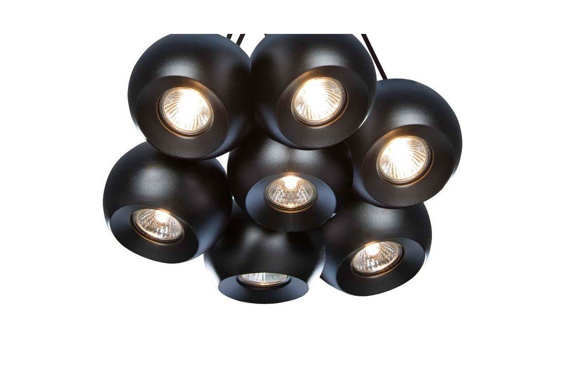 Na obrazie widoczna jest lampa wisząca składająca się z siedmiu czarnych, kulistych kloszy z wbudowanymi żarówkami. Klosze są skierowane w różnych kierunkach, emitując światło.