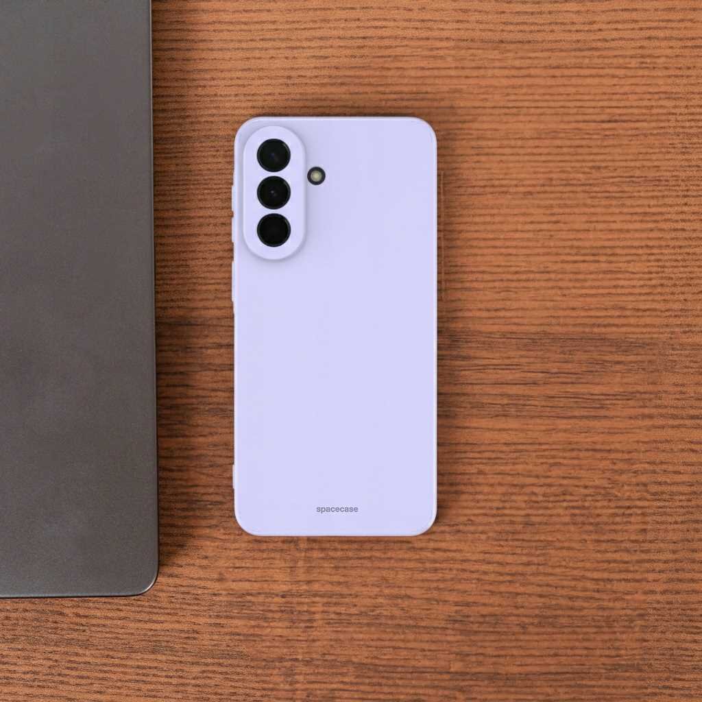 Fioletowe silikonowe etui na telefon z trzema otworami na aparaty i napisem \'spacecase\' na drewnianym tle. Obok widoczna jest część metalowego urządzenia.