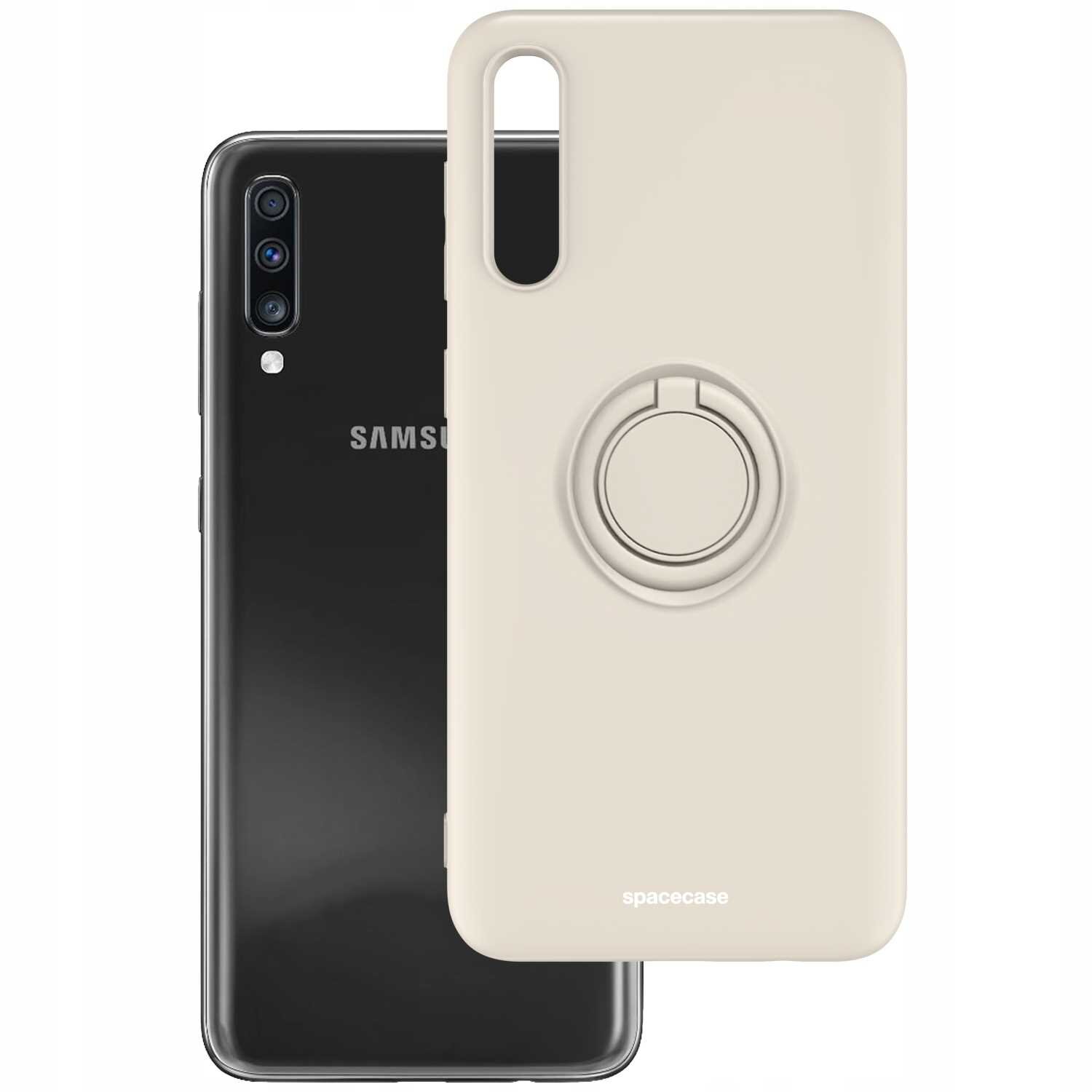 Na obrazie widoczne jest beżowe silikonowe etui z pierścieniem, przeznaczone do telefonu Galaxy A70. W tle znajduje się czarny telefon z logo \'Samsung\'.