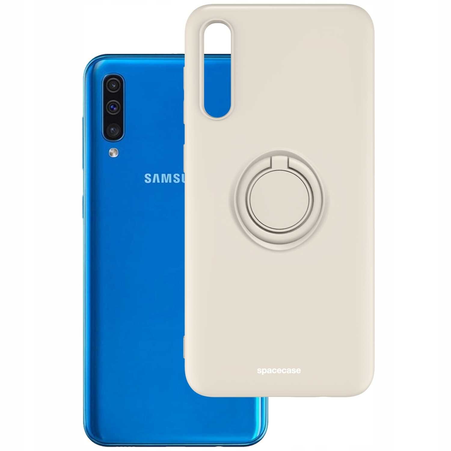 Na obrazie widoczne jest beżowe silikonowe etui z pierścieniem, przeznaczone do telefonu. W tle znajduje się niebieski telefon z logo \'SAMSUNG\'.