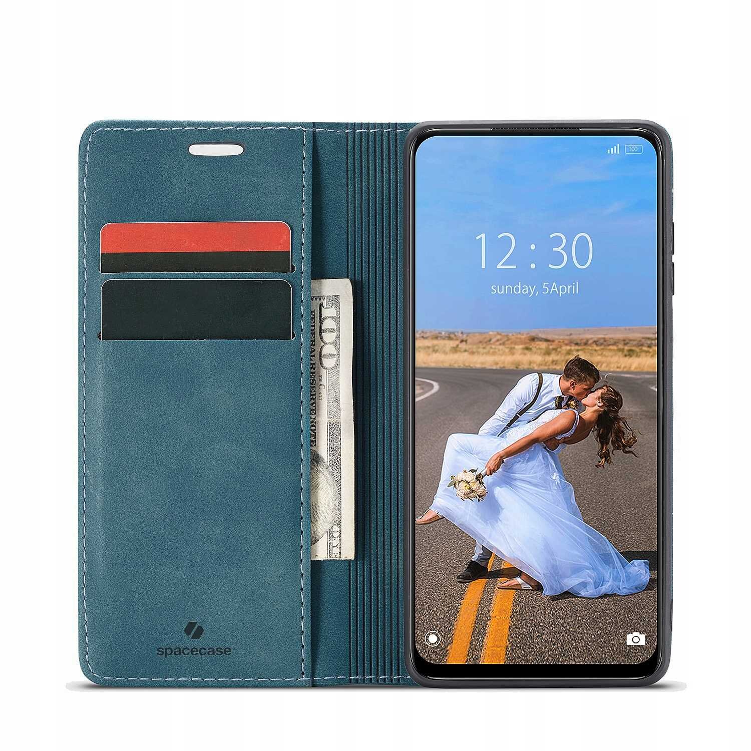 Etui z klapką w kolorze niebieskim z miejscem na karty i banknoty, obok smartfon z wyświetlaczem pokazującym godzinę 12:30, niedziela, 5 kwietnia. Na ekranie telefonu widoczna jest para w strojach ślubnych na drodze.