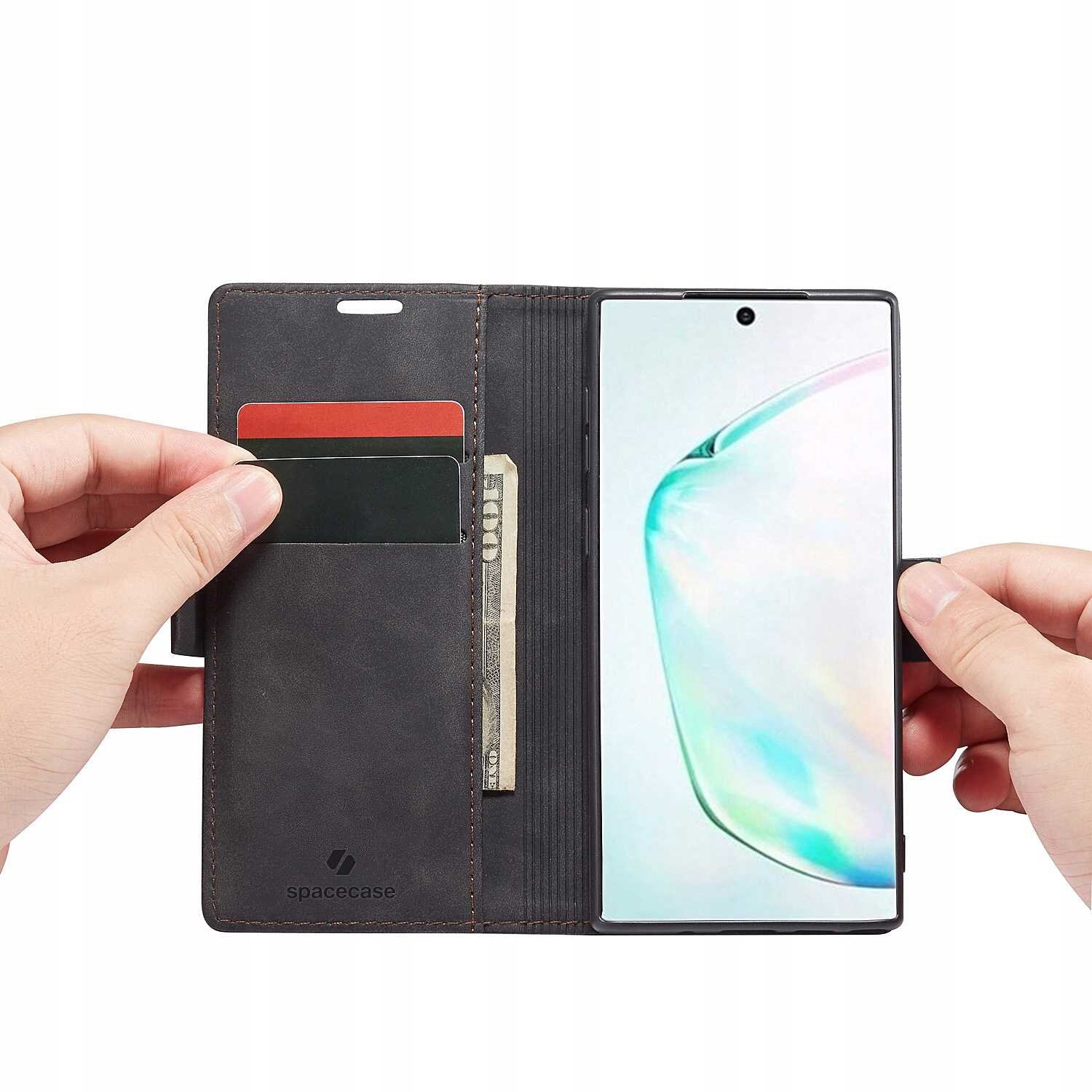 Osoba trzyma otwarte etui z klapką, w którym znajduje się telefon oraz kieszenie na karty i banknoty. Na etui widoczne jest logo \'spacecase\'.