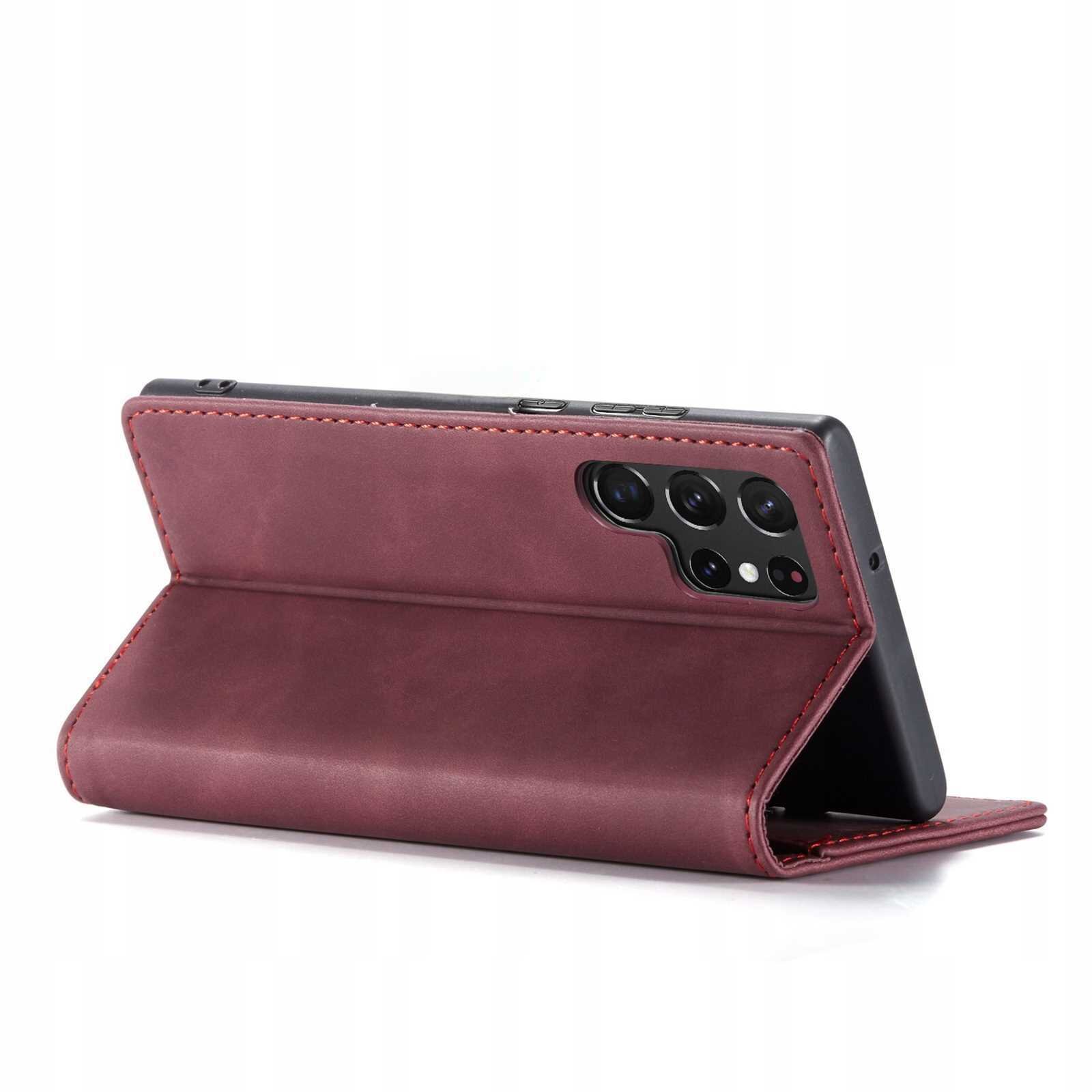 Czerwone etui z klapką ustawione w pozycji stojącej, z widocznymi wycięciami na aparat telefonu. Etui wykonane jest z materiału przypominającego skórę.