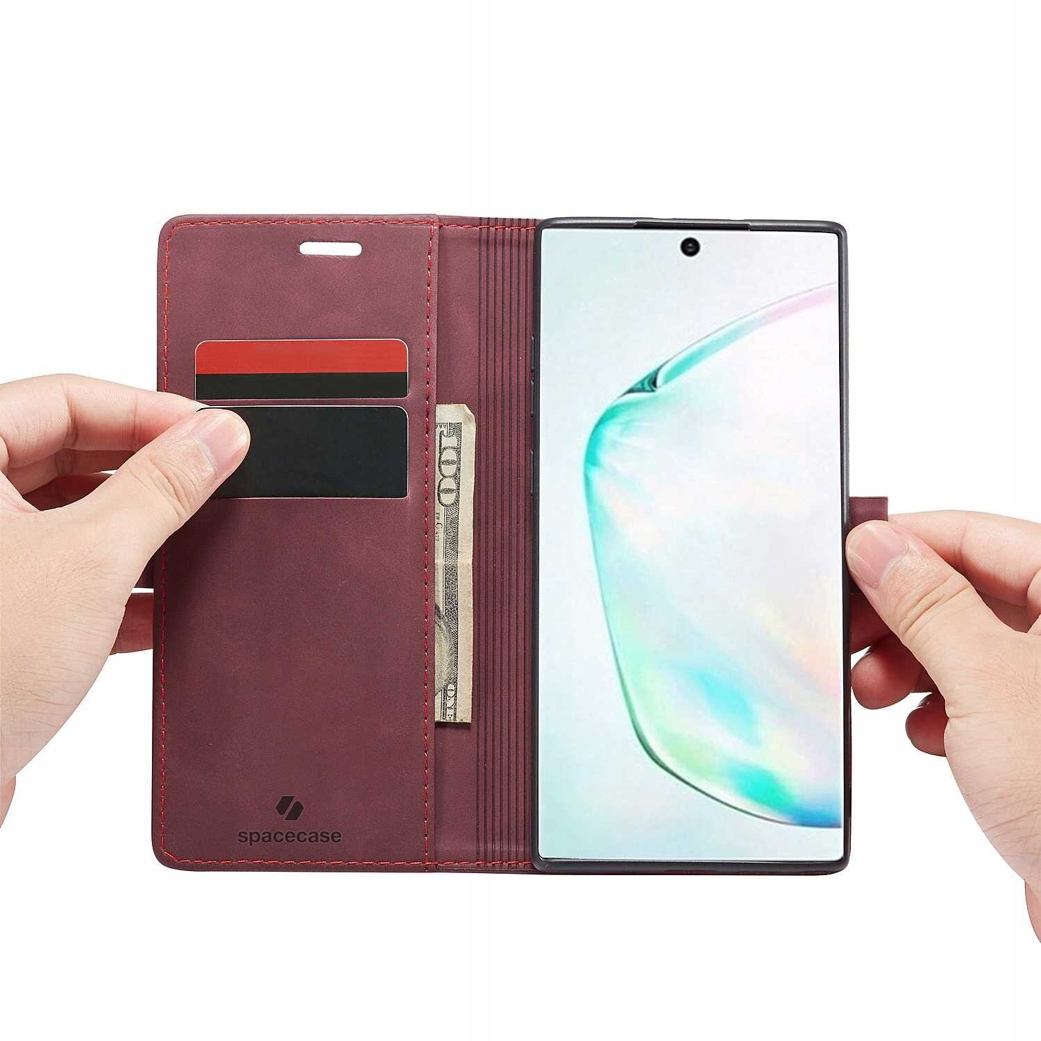 Czerwone etui z klapką na telefon, z miejscem na karty i banknoty, trzymane w dłoniach. Widoczne logo \'spacecase\' na dolnej części etui.