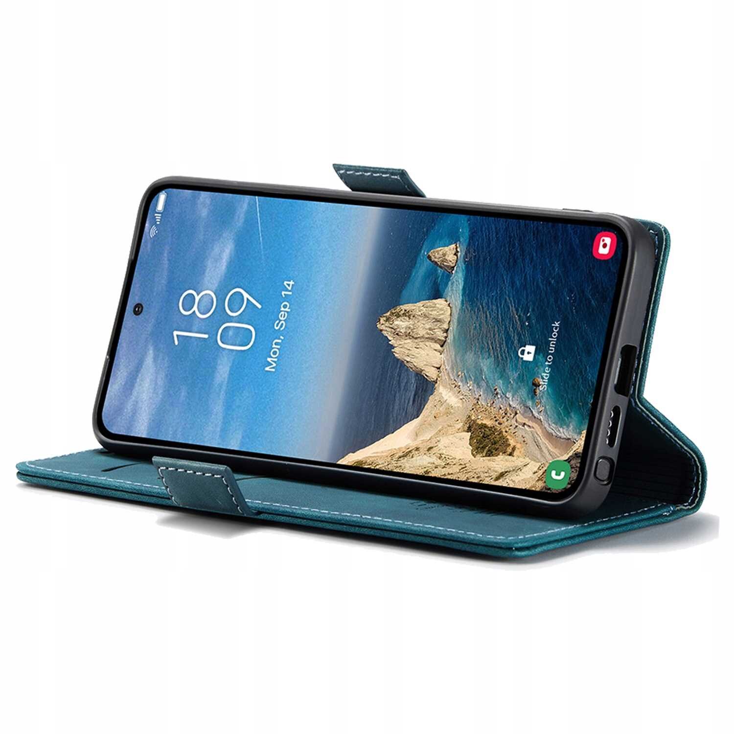 Smartfon w niebieskim etui z klapką, ustawiony w pozycji poziomej. Na ekranie widoczny jest krajobraz z morzem i skałami oraz data \'Mon, Sep 14\'.