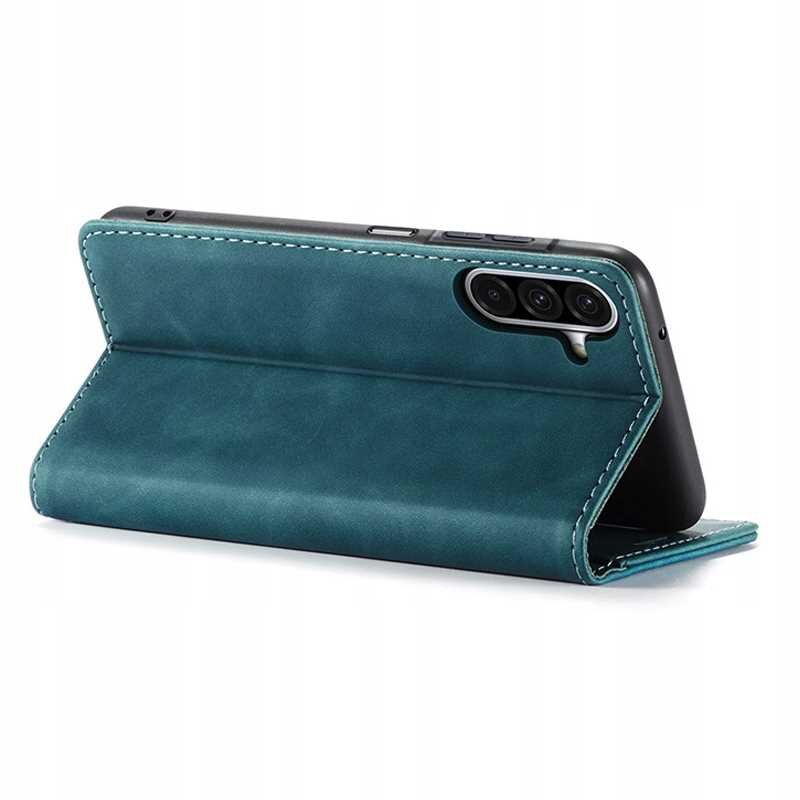 Niebieskie etui z klapką ustawione w pozycji stojącej, z widocznymi trzema otworami na aparat telefonu. Etui ma wyraźne przeszycia na krawędziach.
