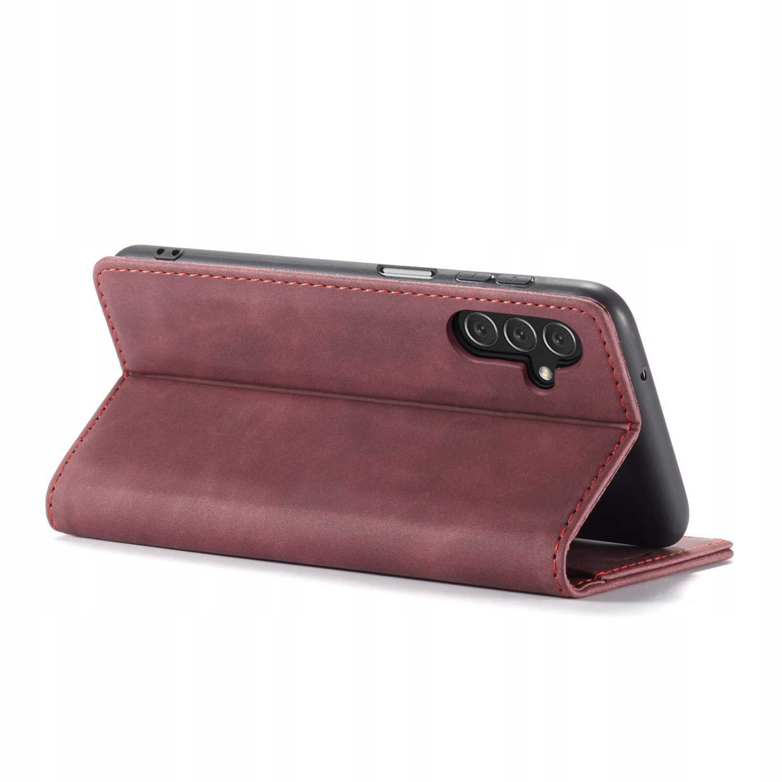Czerwone etui z klapką, ustawione w pozycji stojącej, z widocznymi trzema obiektywami aparatu telefonu. Etui ma gładką powierzchnię i przeszycia na krawędziach.