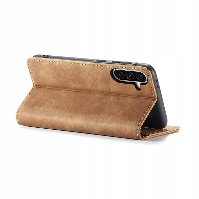Brązowe etui z klapką ustawione w pozycji stojącej, z widocznymi trzema obiektywami aparatu telefonu. Etui ma gładką powierzchnię i przeszycia na krawędziach.