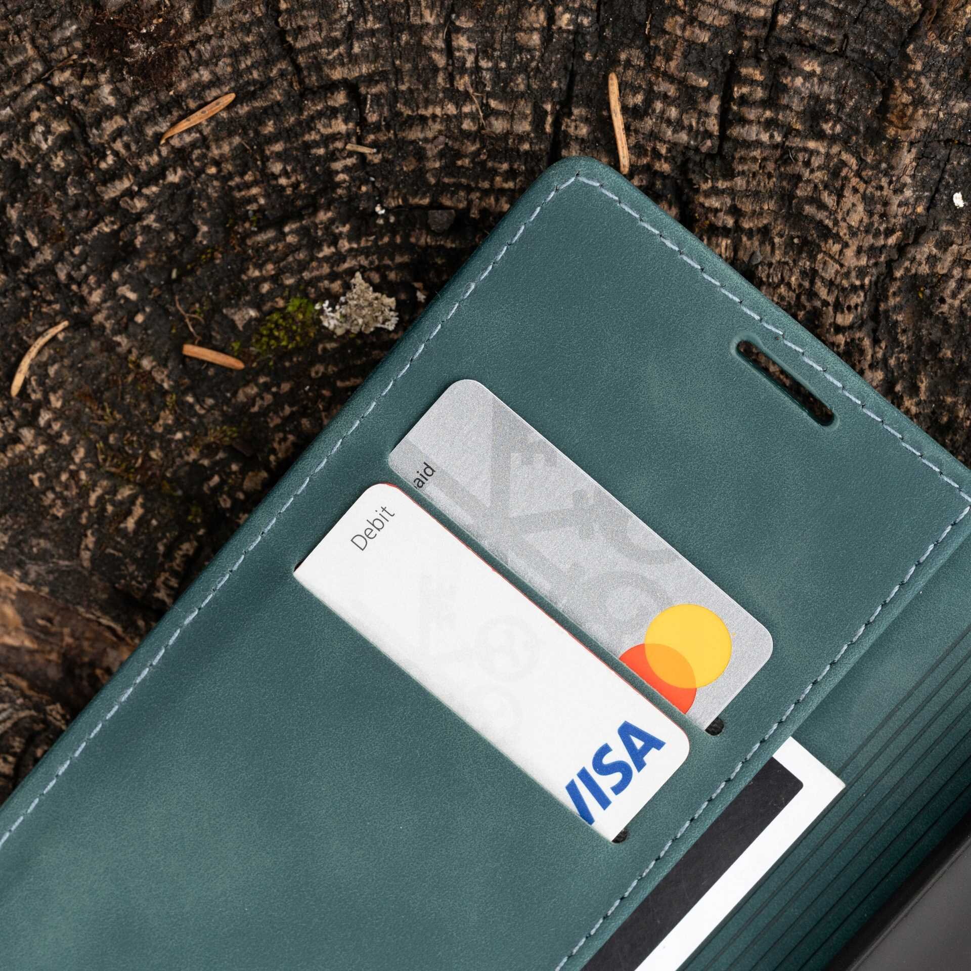 Etui z klapką w kolorze niebieskim leży na drewnianej powierzchni, z widocznymi dwoma kartami płatniczymi w kieszeniach, z logo Visa i Mastercard.