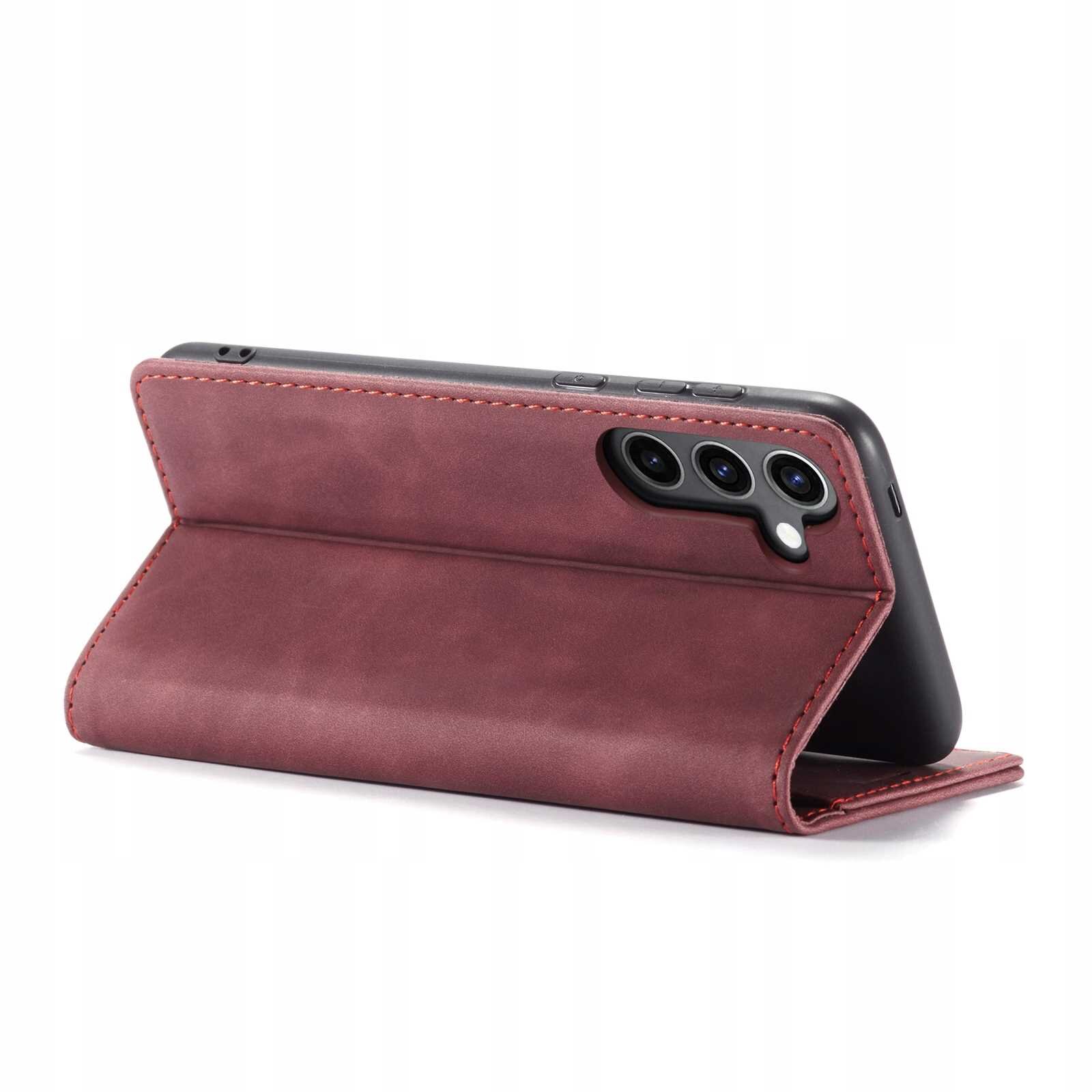 Czerwone etui z klapką ustawione w pozycji stojącej, z trzema widocznymi otworami na aparaty telefonu. Etui ma gładką powierzchnię i widoczne przeszycia na krawędziach.