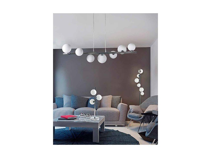 Wnętrze salonu z nowoczesnym wystrojem, w którym znajduje się lampa wisząca z siedmioma kulistymi kloszami. W pomieszczeniu są także szare sofy, stolik kawowy i stojąca lampa z kulistymi kloszami.