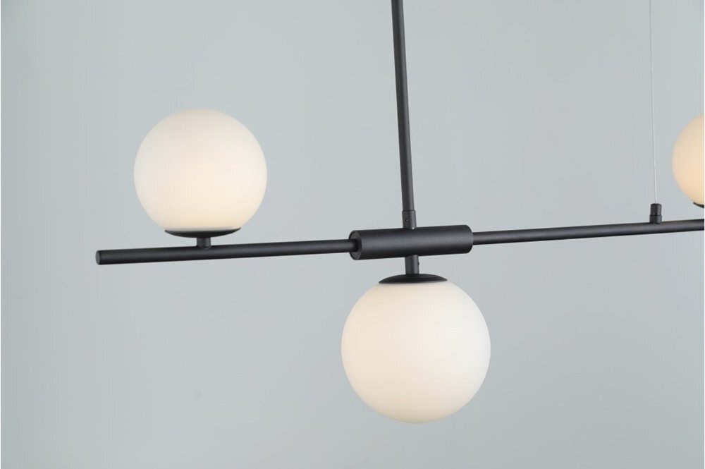 Na obrazie widoczna jest nowoczesna lampa wisząca z trzema kulistymi kloszami w kolorze białym, zamontowana na czarnej, metalowej konstrukcji. Tło jest jednolite i jasne.