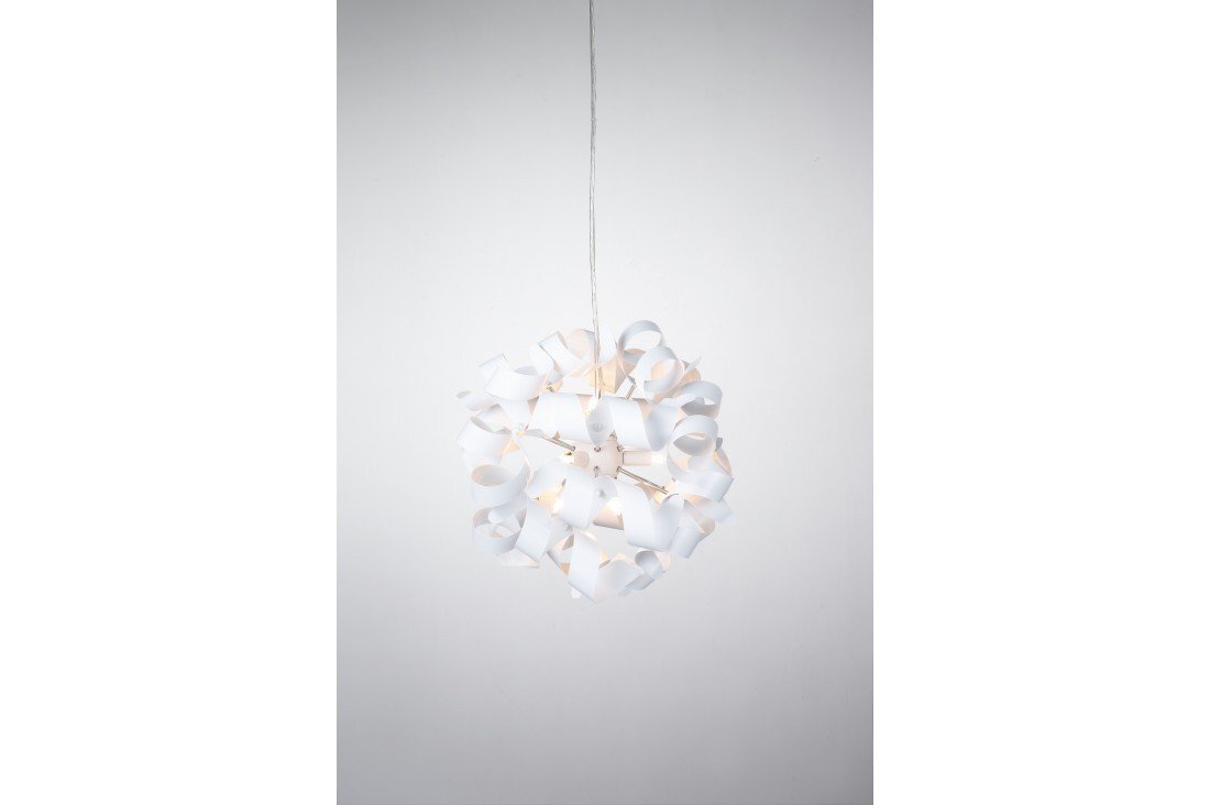 Na obrazie widoczna jest wisząca lampa o kulistym kształcie, złożona z wielu białych, zakrzywionych elementów. Lampa jest zawieszona na cienkim przewodzie na tle jasnej ściany.