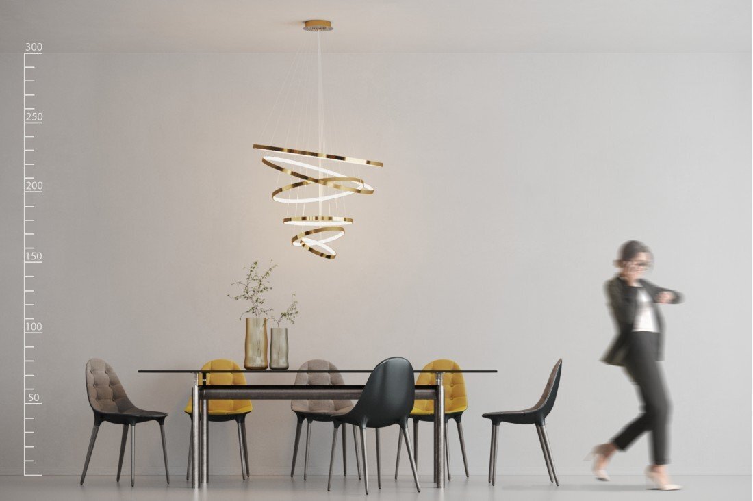 Wnętrze z nowoczesnym stołem i krzesłami, nad którym wisi designerska lampa o spiralnym kształcie. Obok stołu przechodzi osoba ubrana w ciemny strój.