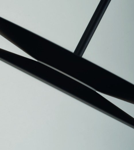 Obraz przedstawia zbliżenie na czarną, nowoczesną lampę wiszącą o eleganckim designie. Lampa ma prostą, geometryczną formę z widocznymi cienkimi elementami.
