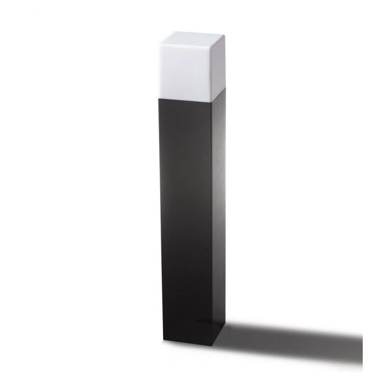 Na obrazie widoczna jest lampa zewnętrzna w formie prostokątnego słupka, z białą górną częścią i czarną dolną częścią. Lampa stoi na jasnym tle, rzucając cień na podłoże.