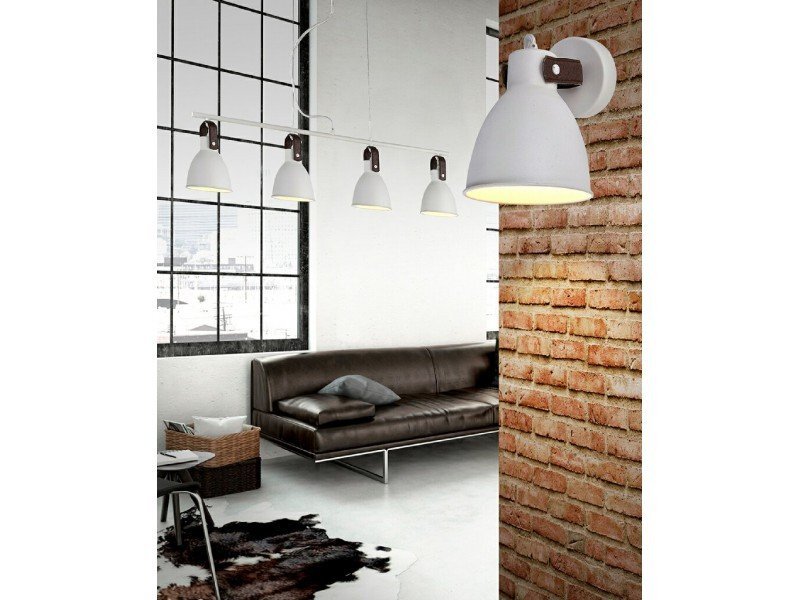 Wnętrze z industrialnym wystrojem, w którym znajduje się czarna, skórzana sofa oraz lampa wisząca z czterema białymi kloszami. Ściana z cegły dodaje charakteru przestrzeni.