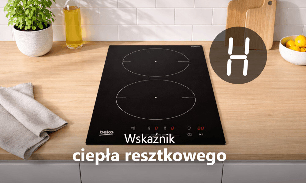 Na blacie kuchennym znajduje się czarna płyta indukcyjna z dwoma polami grzewczymi, obok której leży ściereczka i stoi butelka z oliwą. Widoczny jest tekst: \'Wskaźnik ciepła resztkowego\'.
