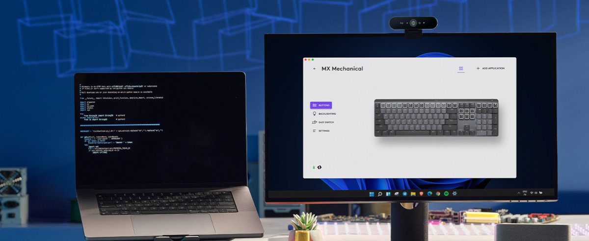 Na obrazie widać dwa ekrany: laptop z wyświetlonym kodem oraz monitor z obrazem klawiatury i tekstem \'MX Mechanical\'. W tle znajduje się niebieska ściana z geometrycznym wzorem.