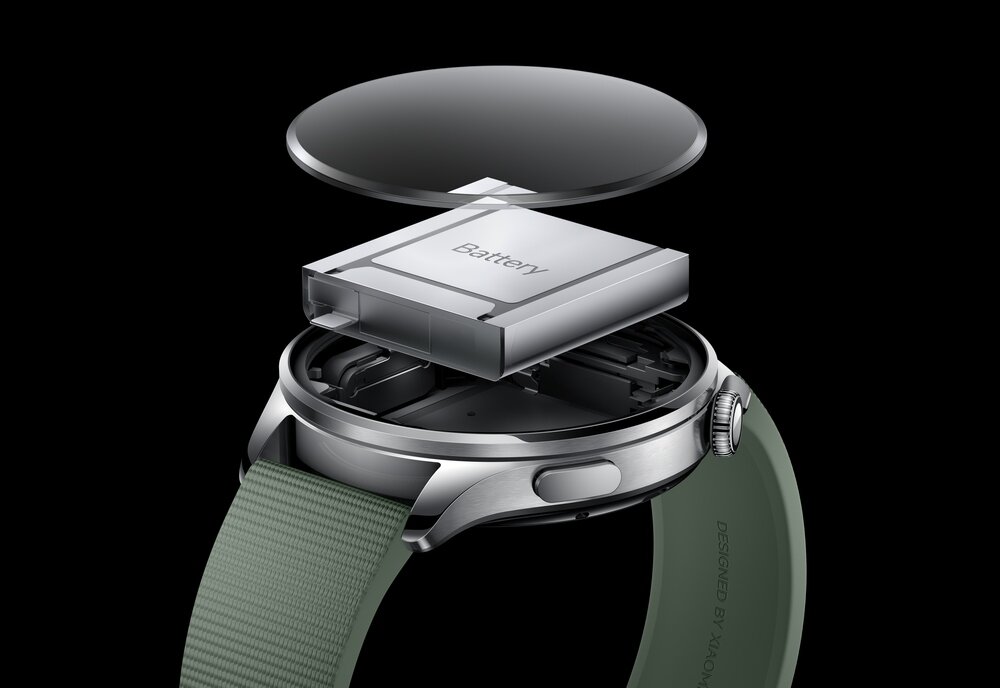 Obraz przedstawia rozłożony smartwatch z widoczną baterią oznaczoną napisem \'Battery\'. Pasek zegarka jest zielony, a na kopercie widnieje napis \'DESIGNED BY XIAOMI\'.