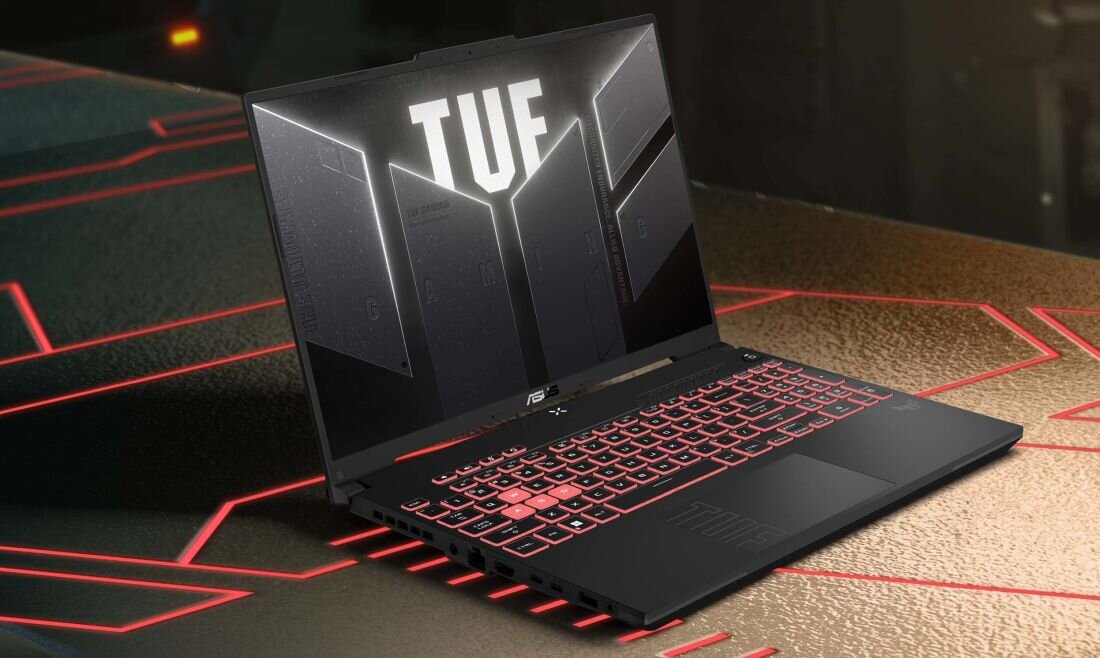 Laptop z podświetlaną klawiaturą i ekranem wyświetlającym logo \'TUF\'.