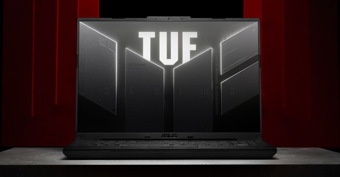 Na ekranie laptopa widoczny jest napis \'TUF\' na tle geometrycznych kształtów. Obudowa laptopa jest ciemna, a w dolnej części ekranu znajduje się logo ASUS.