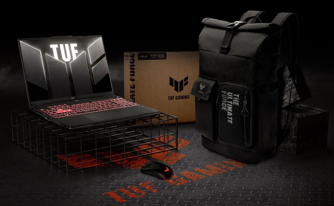 Na obrazie znajduje się laptop z podświetlaną klawiaturą i ekranem z napisem \'TUF\', obok którego leży myszka. W tle widoczny jest plecak z napisem \'THE ULTIMATE FORCE\' oraz pudełko z logo \'TUF GAMING\'.