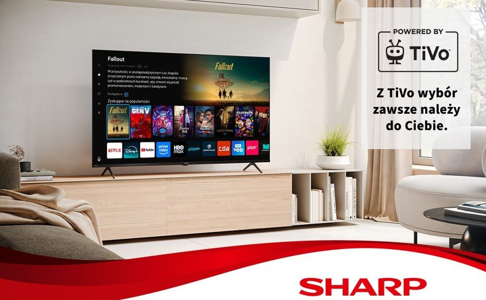 Telewizor wyświetla interfejs z aplikacjami takimi jak Netflix, Disney+, Prime Video i inne. Na obrazie widoczne jest logo SHARP oraz napis \'POWERED BY TiVo Z TiVo wybór zawsze należy do Ciebie.\'