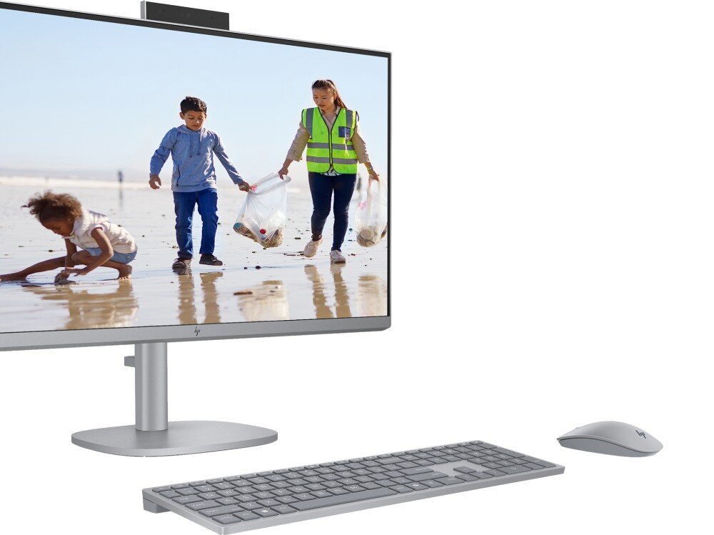 Komputer All in One HP OmniStudio X 32-C0005NW Monitor komputerowy z zamontowaną na górze kamerą internetową, wyświetlający zdjęcie dzieci sprzątających plażę, obok klawiatura i mysz