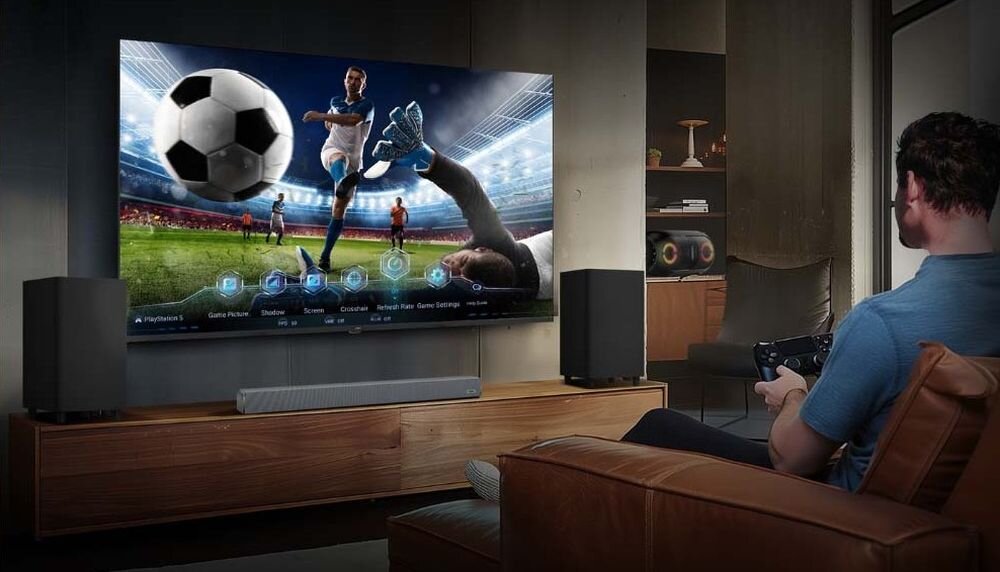 HAIER H85S80GUX telewizor Game Mode VRR ALLM niski input lag dla graczy, osoba trzymająca kontroler w ręku