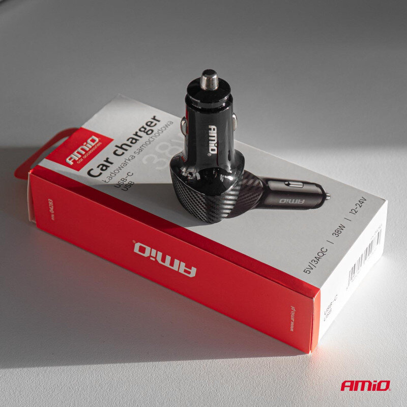 Na obrazie widoczna jest czarna ładowarka samochodowa z logo \'AMiO\', umieszczona na pudełku z napisem \'Car charger Ładowarka Samochodowa USB-C USB-A\'. Pudełko jest czerwono-białe z dodatkowymi informacjami: \'5V/3A QC\', \'38W\', \'12-24V\'.