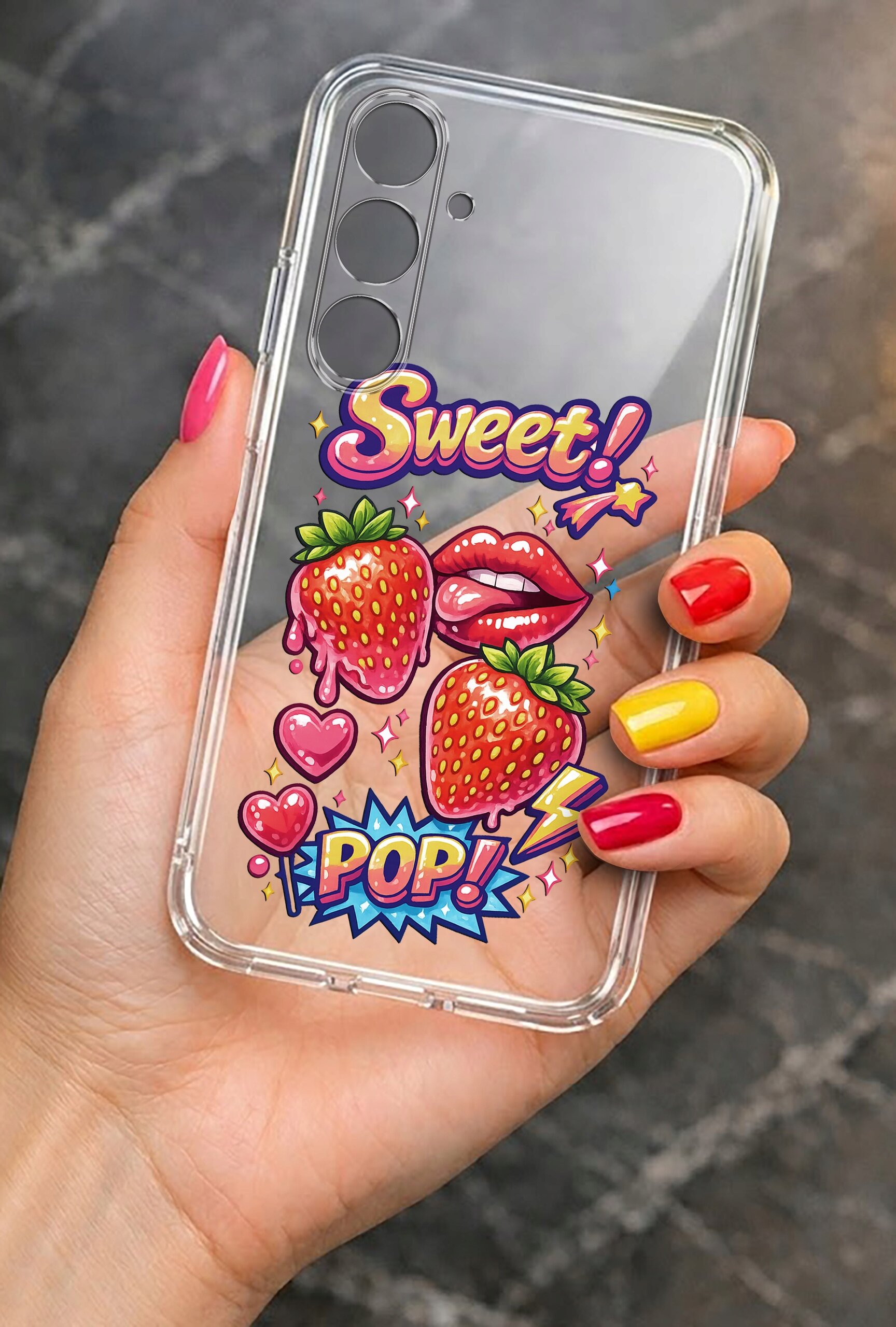 Przezroczyste etui na telefon z kolorowymi grafikami przedstawiającymi truskawki, usta, serca oraz napisy \'Sweet!\' i \'POP!\'. Etui trzymane jest w dłoni z pomalowanymi paznokciami na różne kolory.