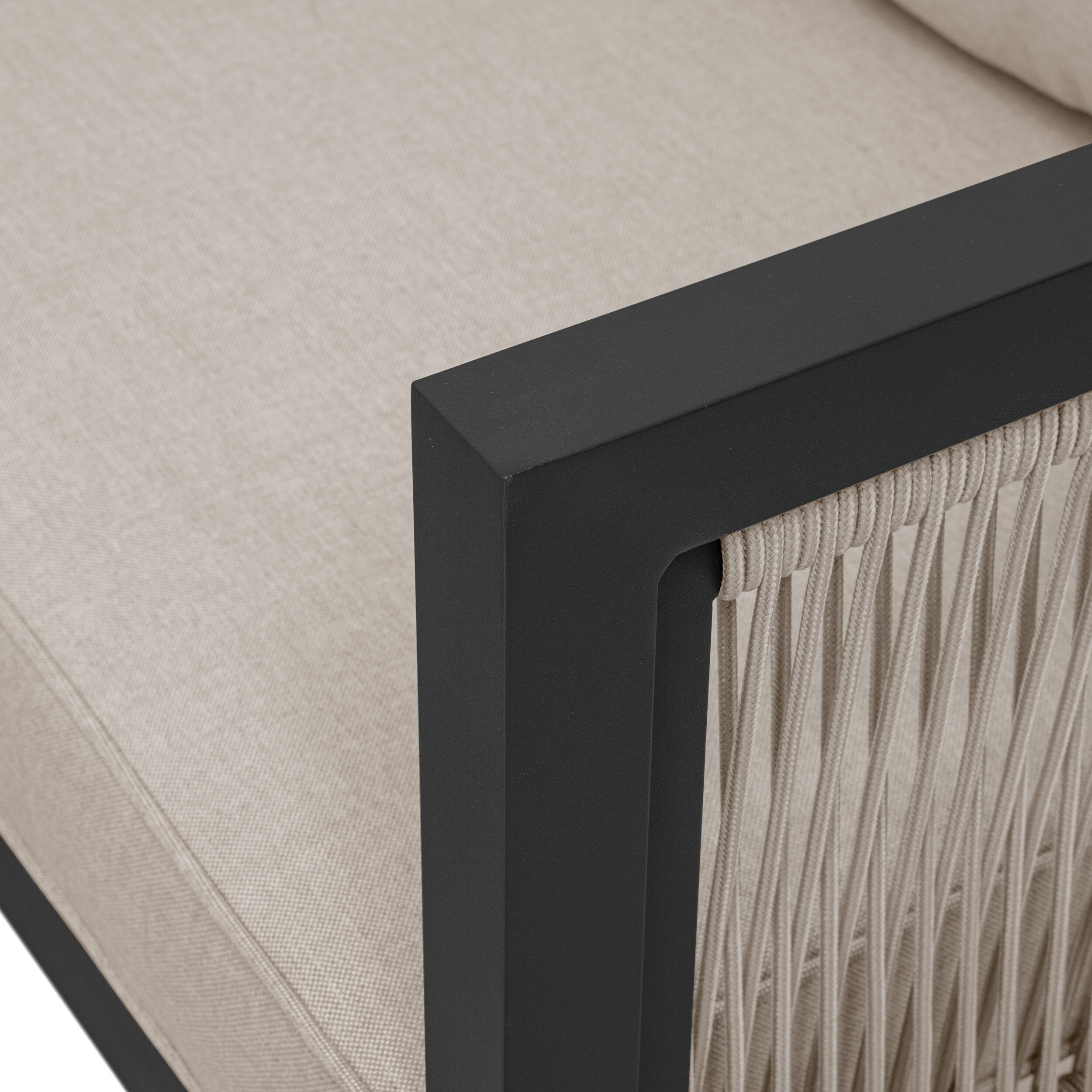 Zbliżenie na narożnik mebla ogrodowego z beżowym materiałem i czarną aluminiową ramą. Widać również plecionkę z jasnego sznurka na boku mebla.
