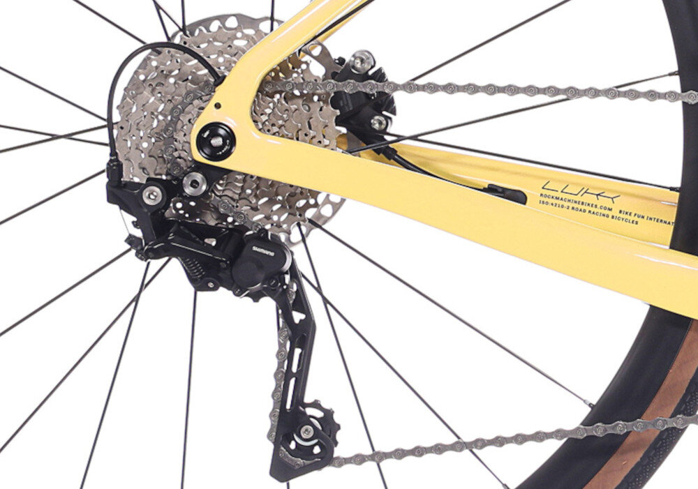 Rower gravel ROCK MACHINE Lukk Cr 65 U21 28 cali Żółty zbliżenie na tylną przerzutkę białe tło przerzutki SHIAMNO 20 przełożeń duża wytrzymałość sprawne działanie zmiana biegów jest płynna i bezproblemowa Przedni i tylny napęd SHIMANO CUES komfortowa kadencja łatwiej zachować rytm jazdy