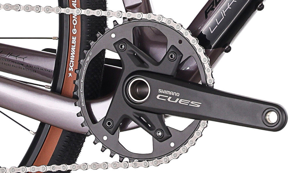 Rower gravel ROCK MACHINE Lukk CR 30 U21 28 cali Fioletowy zbliżenie na korbę białe tło wkład suportu SHIMANO typu BSA korba SHIMANO typu CUES typu FC-U6030,42T, 170 mm kaseta SHIMANO typu CS-LG400-11 o zakresie 11–50T odpowiednie przełożenie szeroki zakres kasety odpowiednio dobrane komponenty